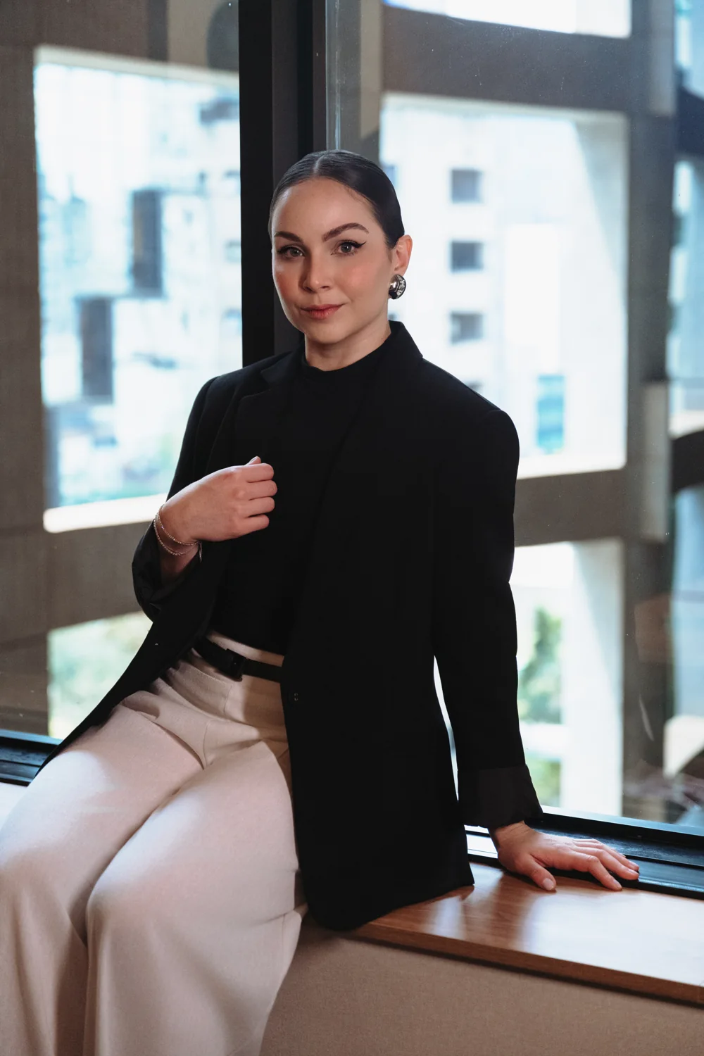 Thayna Milani sentada junto à janela do escritório